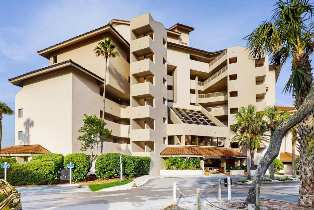 a building with palm trees in front of it at Ocean Front Hotel Side Condo with Balcony, WiFi & Shared Pool in Fernandina Beach