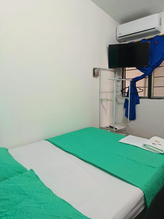 ein Zimmer mit einem Bett mit einer grünen Decke und einem Fernseher in der Unterkunft Hotel Efata in Apartadó