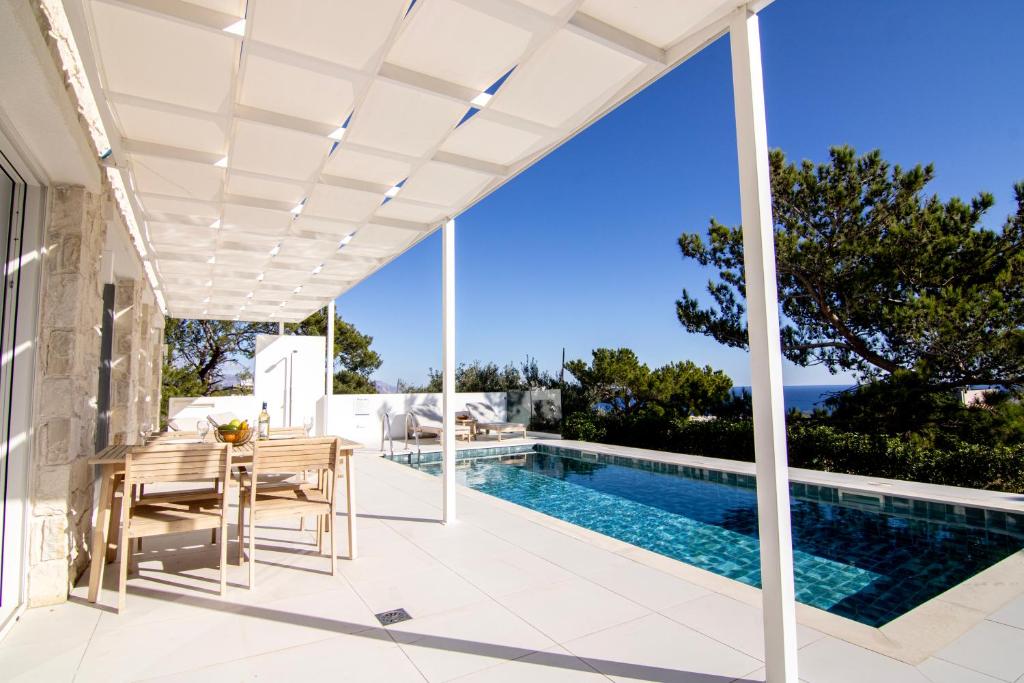 a white pergola over a patio with a swimming pool at serene villas in Ierapetra