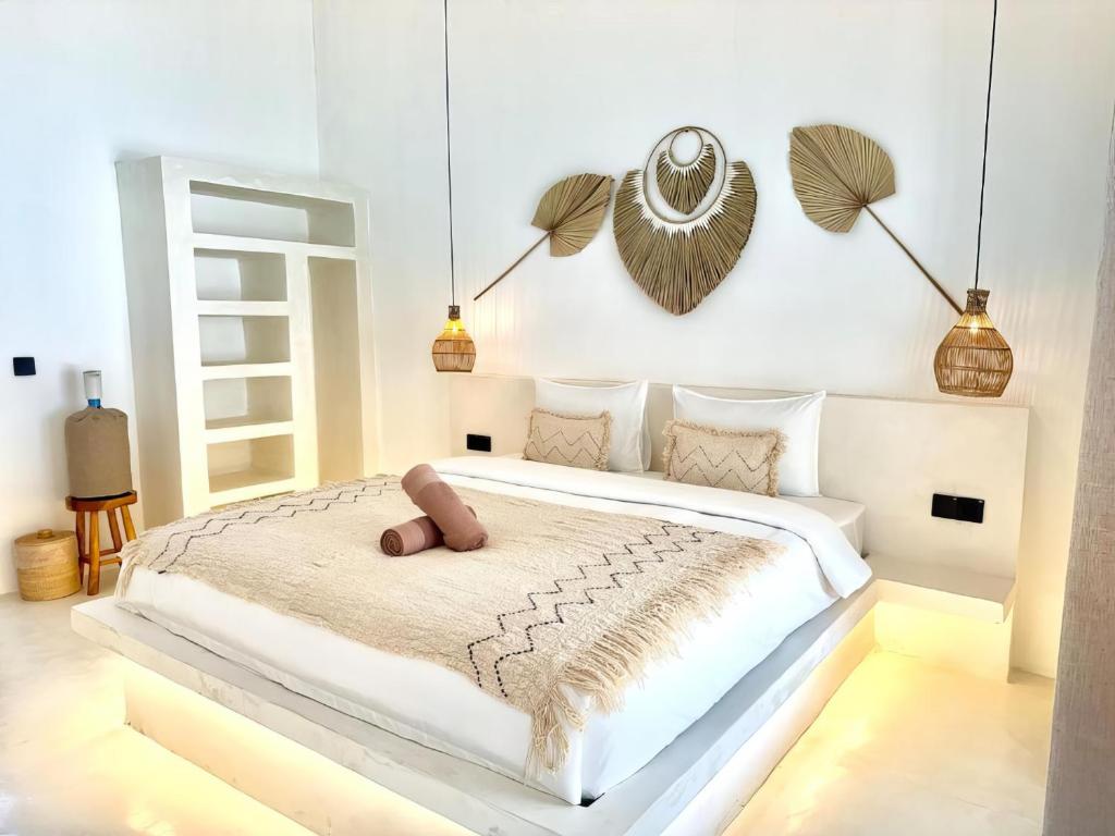 a white bedroom with a large white bed with pillows at Sola Rooms in Kuta Lombok