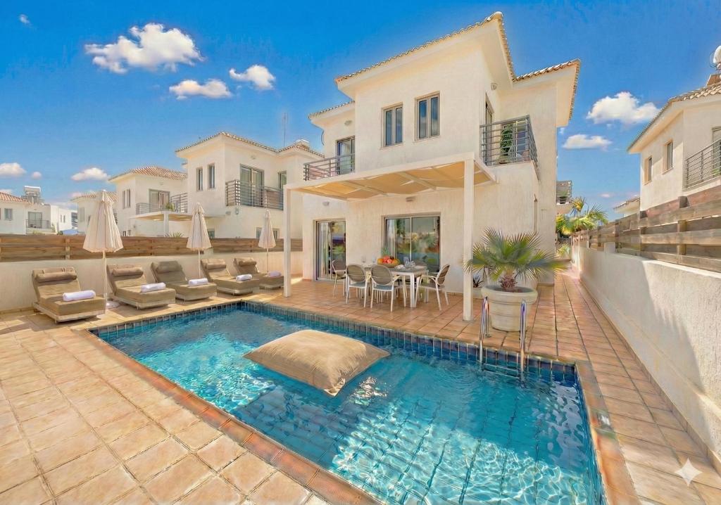 a swimming pool in front of a house at Fig Tree Beach villa Three in Protaras