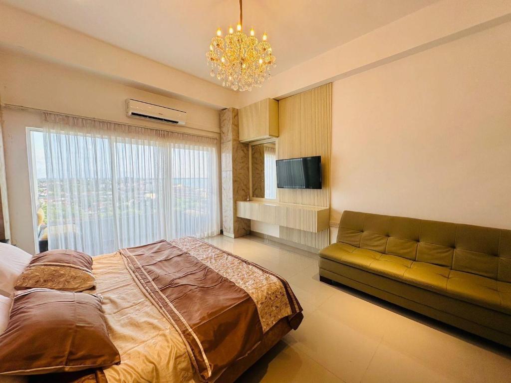a bedroom with a bed and a couch and a chandelier at Azure Luxury Apartment Luxury Stay Near Airport Negombo in Negombo