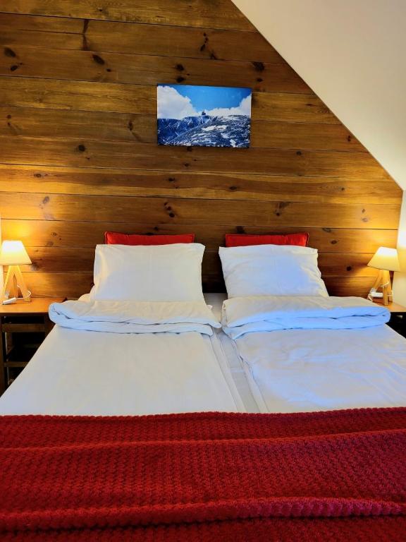 a bedroom with two beds and a wooden wall at To Tutaj in Szklarska Poręba