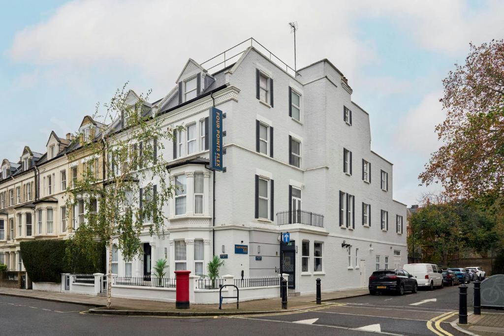a white building on the corner of a street at Four Points Flex by Sheraton London Kensington Olympia in London