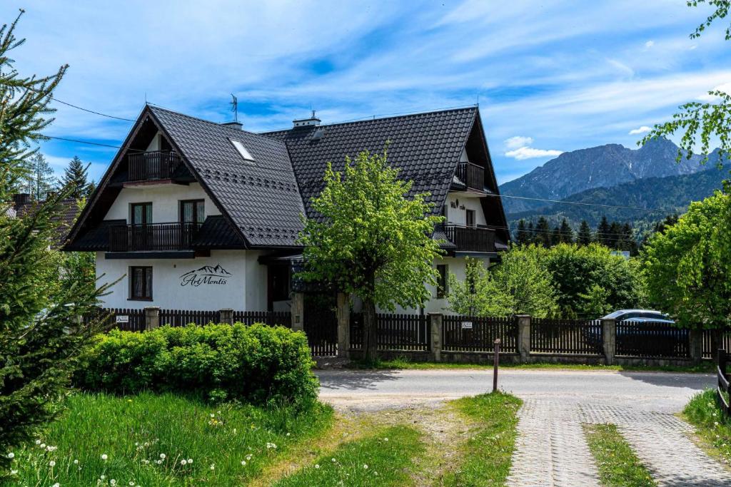 a house with a black roof and a fence at Willa ArtMontis in Kościelisko