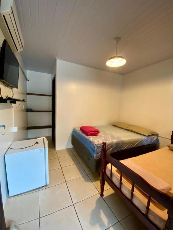 a room with two beds and a tv in it at Hospedaria aconchego master in Garopaba
