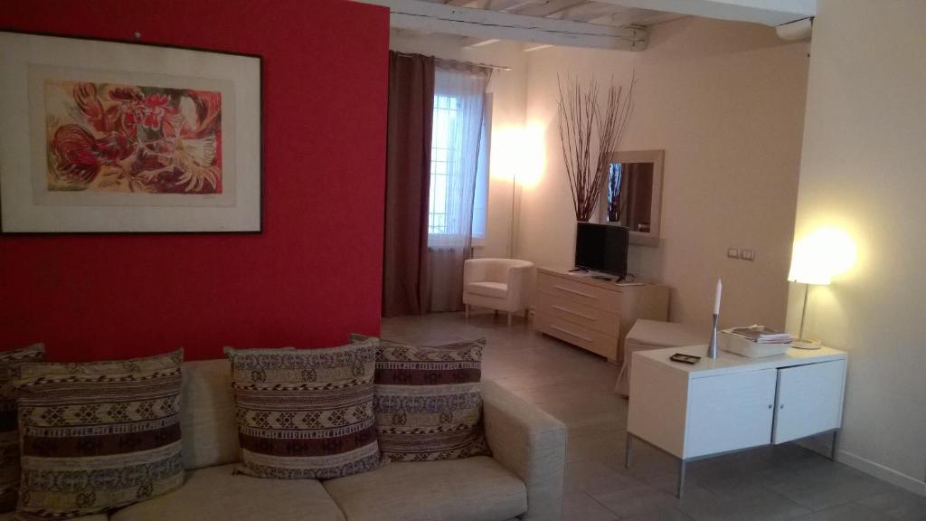 a living room with a couch and a red wall at Agorà Residenza in Mantova