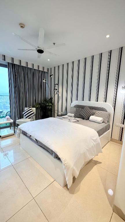 a bedroom with a large white bed with striped walls at Zebra Luxe Loft Studio with patio in Gurgaon