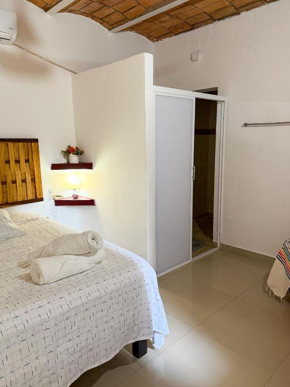 a white bedroom with a bed and a window at Casa Baluana vive Sayulita a un paso de todo in Sayulita