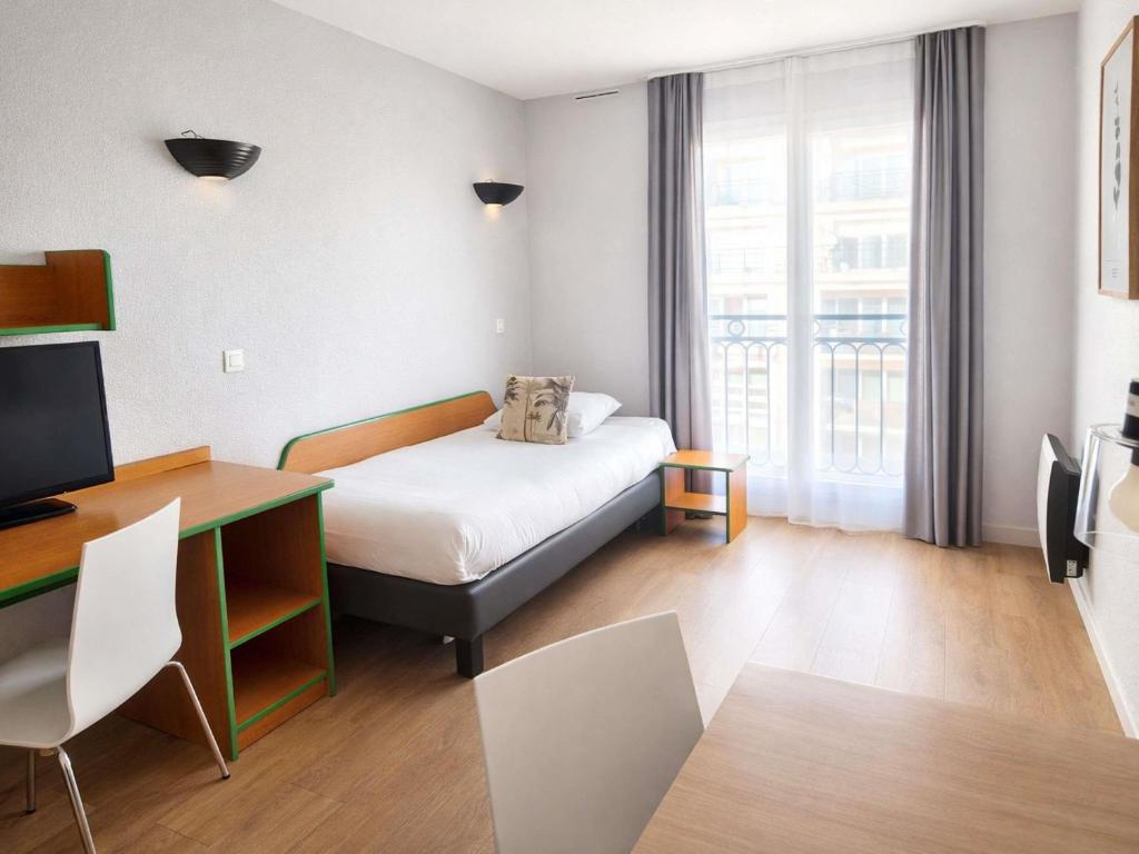 a room with a bed and a desk and a television at Aparthotel Adagio Access Paris Maisons-Alfort in Maisons-Alfort