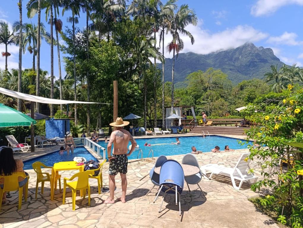 a man in a hat standing next to a swimming pool at Pousada e Restaurante Dona Siroba in Morretes