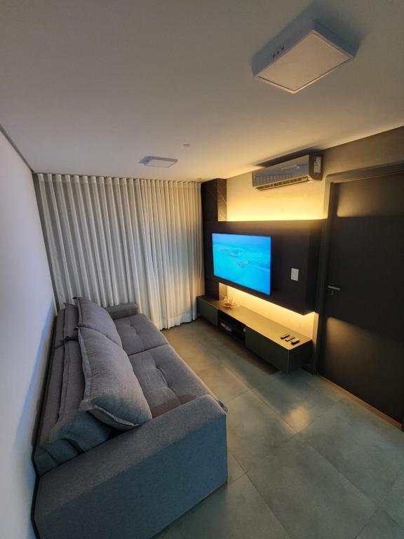 a living room with a couch and a flat screen tv at Apartamento Edifíco Prestige in Marechal Deodoro