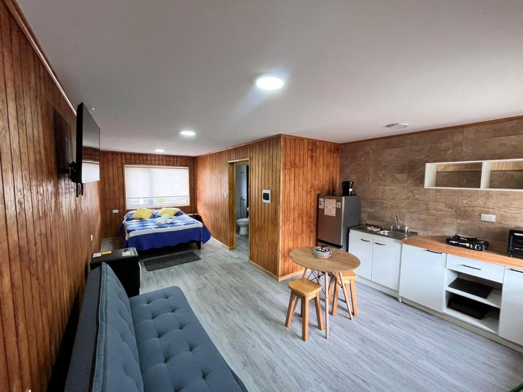 a room with a bed and a kitchen with a table at Departamentos Confluencia in Cochrane