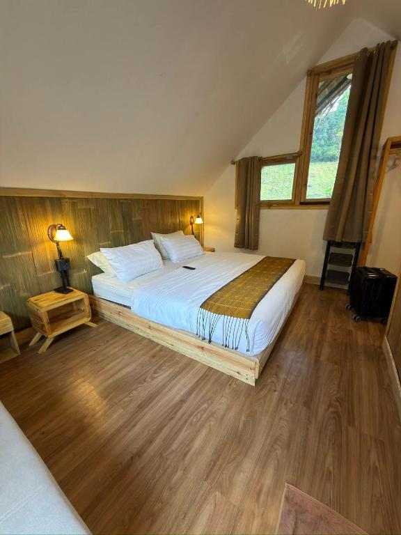 a bedroom with a large bed with wooden floors at A-Frame House บ้านเอเฟรม แดลอร์ปู in Ban Yang