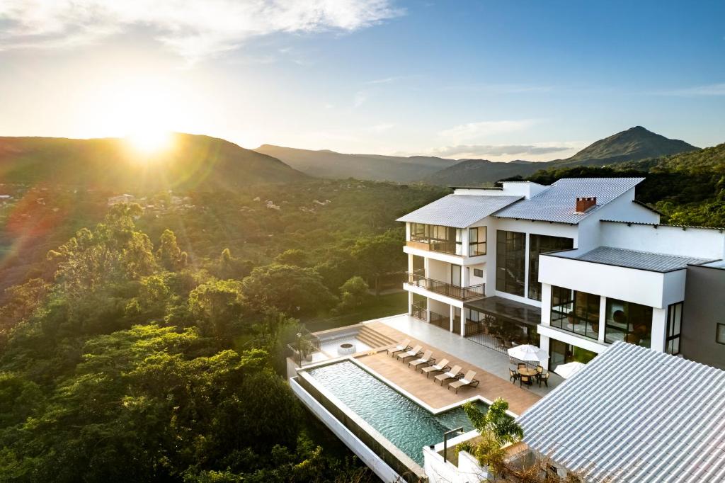 an aerial view of a villa with a pool and the sun setting at Casa do Valle Hotel Boutique - Vale do Capão in Vale do Capao