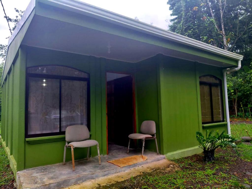 two chairs sitting in the front of a green house at Inmoexito Eco Tours in Upala