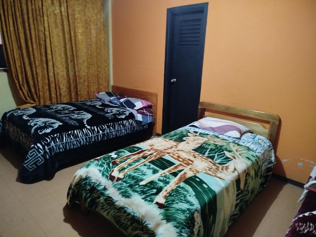two beds in a room with a bedskirts at Hotel atahualpa in Pasto