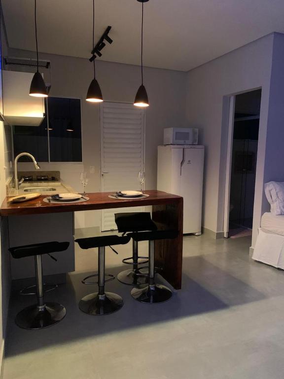 a kitchen with a island with four bar stools at Lua Nova Studio II in Caraguatatuba