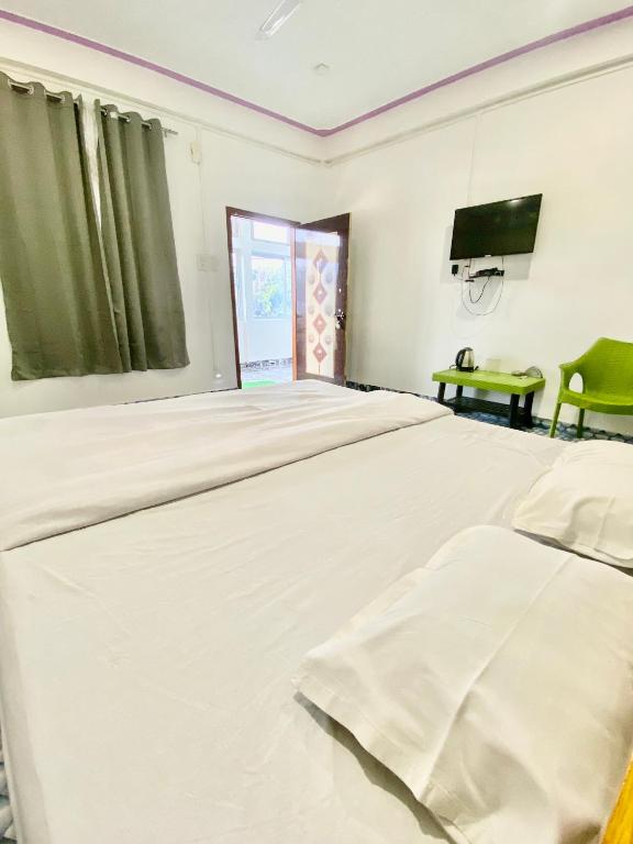 a bedroom with two beds and a flat screen tv at Juihal Residency & Kitchen in Kāziranga