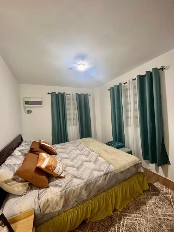 a bedroom with a large bed with green curtains at M&Js Place in Cebu City