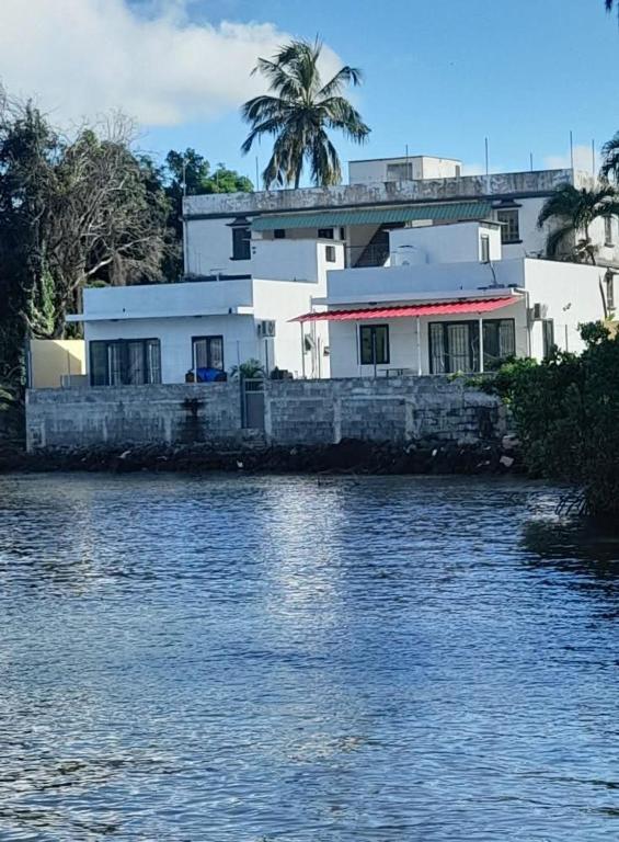 a house on the shore of a body of water at Ashan Laksh Bungalow in Grande Rivière Sud Est