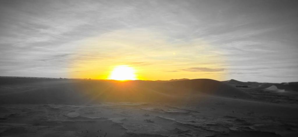 a sunset in the desert with the sun in the sky at Desert feet in Mhamid