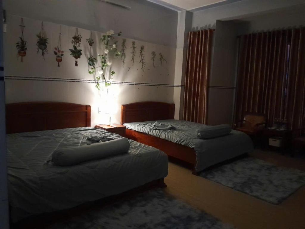 a bedroom with two beds and a lamp on the wall at LUNA House in Hue