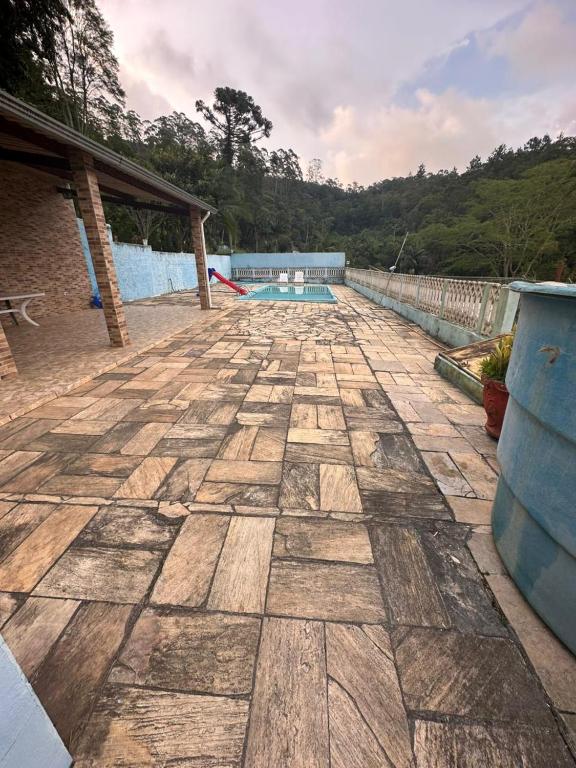 a stone patio with a swimming pool in the background at Chácara sol nascente in Suzano