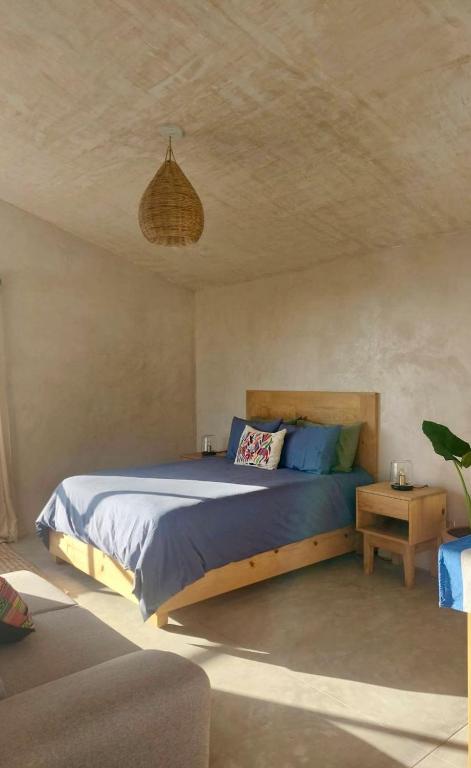 a bedroom with a bed with blue sheets and a ceiling at Casita Atardecer in Todos Santos