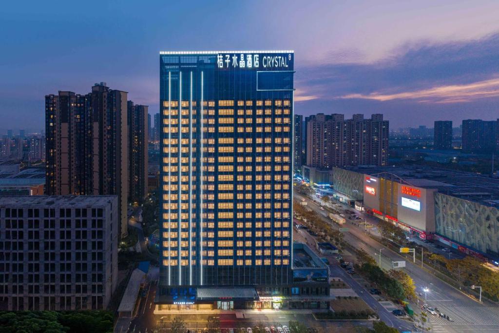 a tall building with lights on in a city at Orange Crystal Hotel Wuhan Jinyinhu in Dongxihu