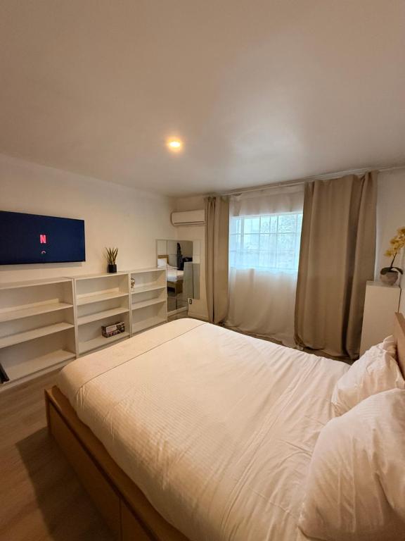a bedroom with a large white bed and a flat screen tv at Garden and chill in Tijuana