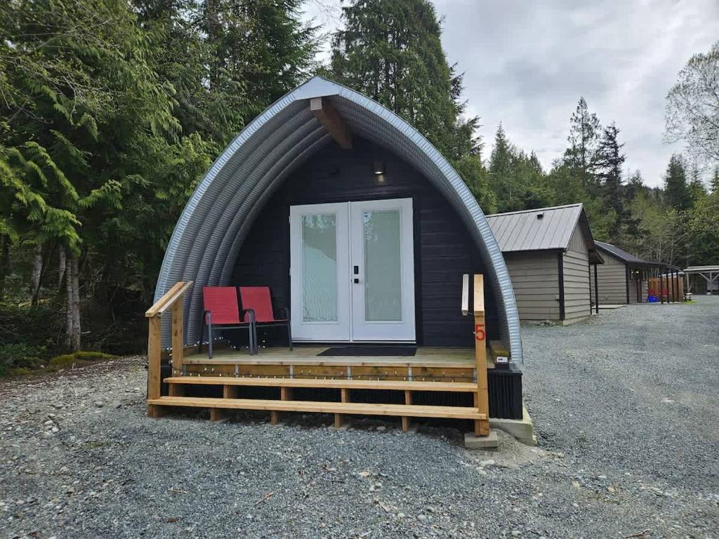 a dome house with a porch and two chairs in it at Stylish Cabin Escape w - Kitchenette & Ensuite Bath in Port Renfrew
