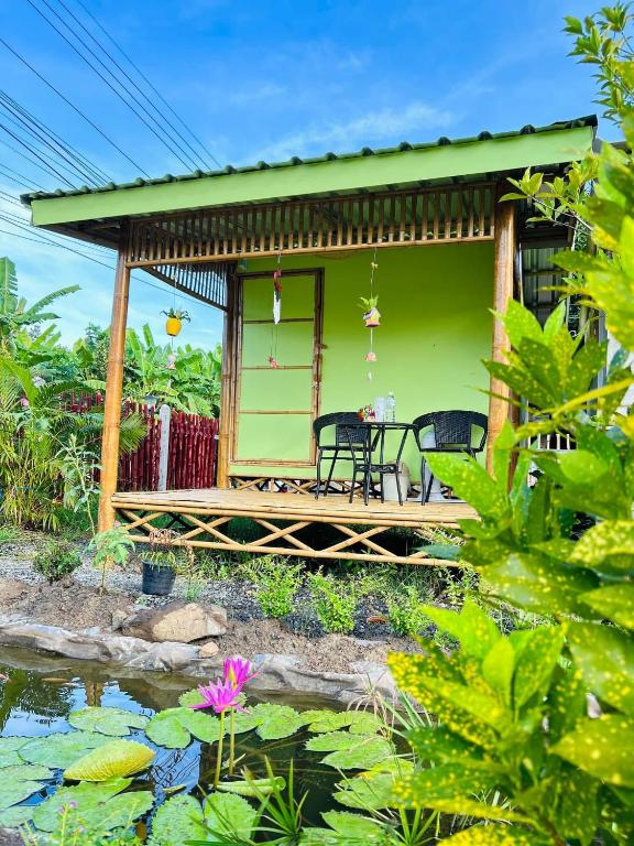 a green house with a table and chairs on a deck at พีเจ คิงดอม โฮมสเตย์ in Buriram