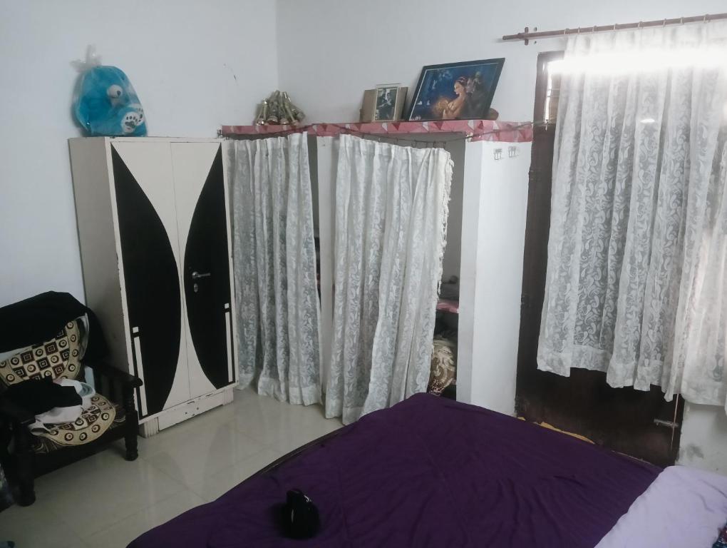 a bedroom with a bed and a window with curtains at Rajwaniya home in Jaipur