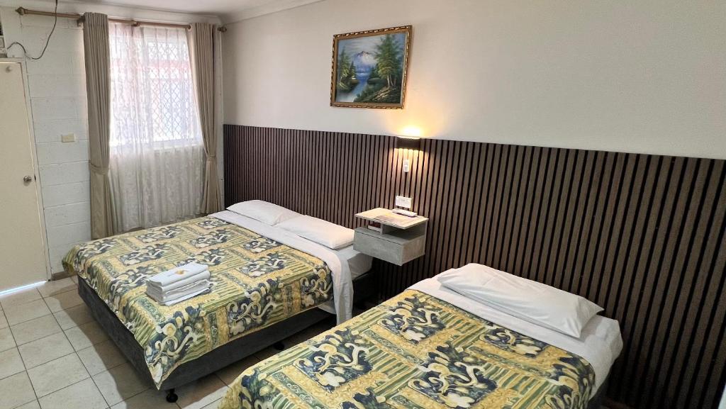 a hotel room with two beds and a table with a lamp at iGrand Motel in Moree