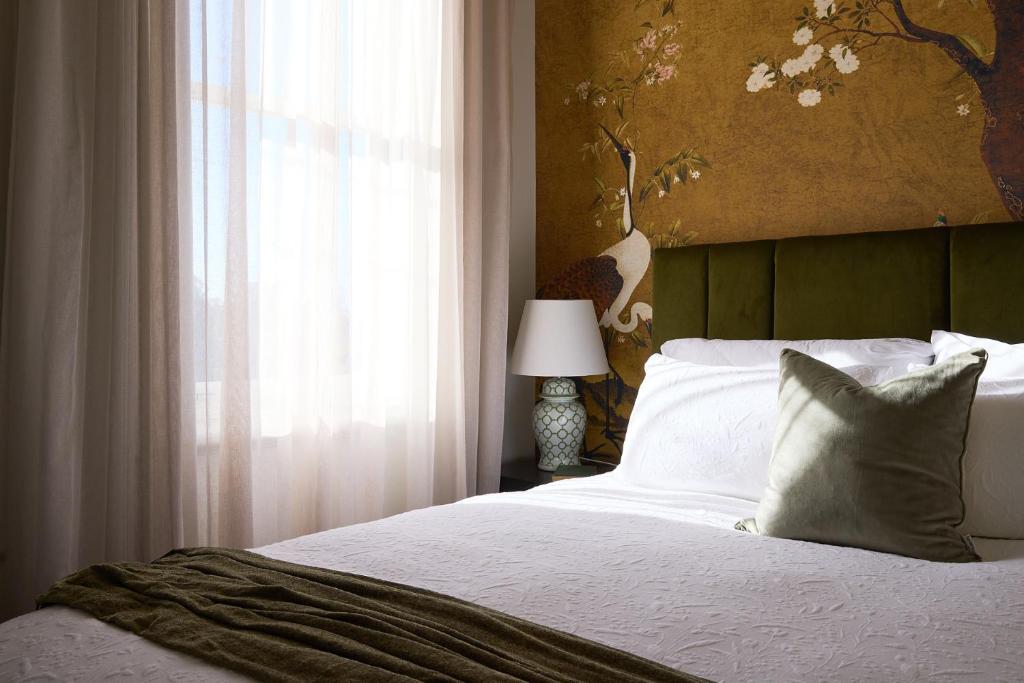 a bedroom with a white bed with a window and a lamp at The Royal Queenscliff in Queenscliff