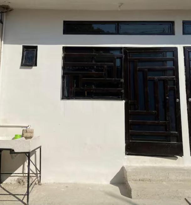 a white building with a black door and a table at Posada de pasada in Iguala de la Independencia
