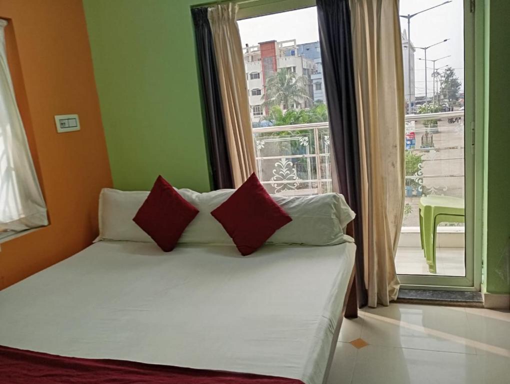 a bed with red pillows in a room with a window at Zeromiles Green Park in Digha