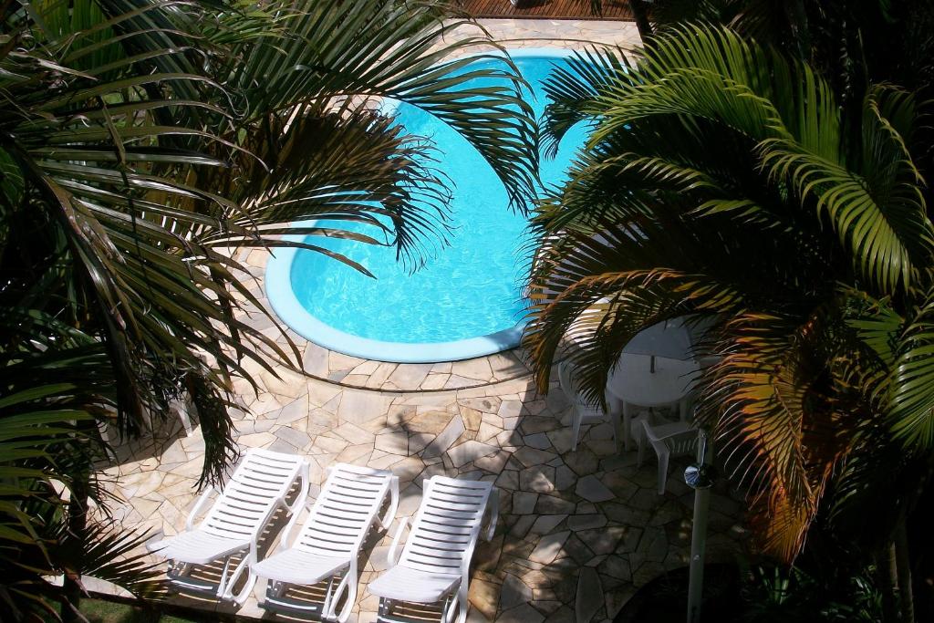 a group of white chairs next to a swimming pool at Pousada Farol da Barra in Florianópolis