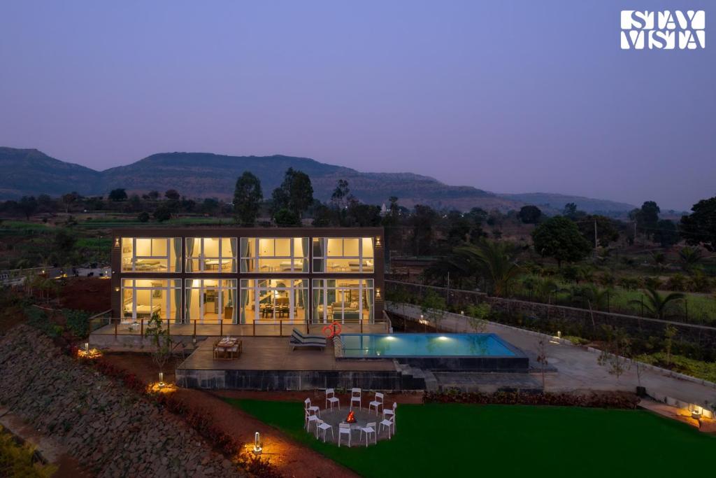a large house with a pool in front of it at StayVista at Crimson Bleu - Bonfire & Pet Friendly in Pune