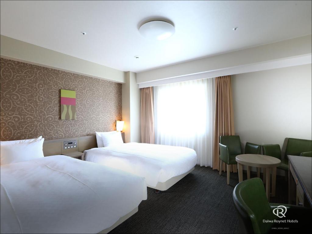 a hotel room with two beds and a table and chairs at Daiwa Roynet Hotel Takamatsu in Takamatsu