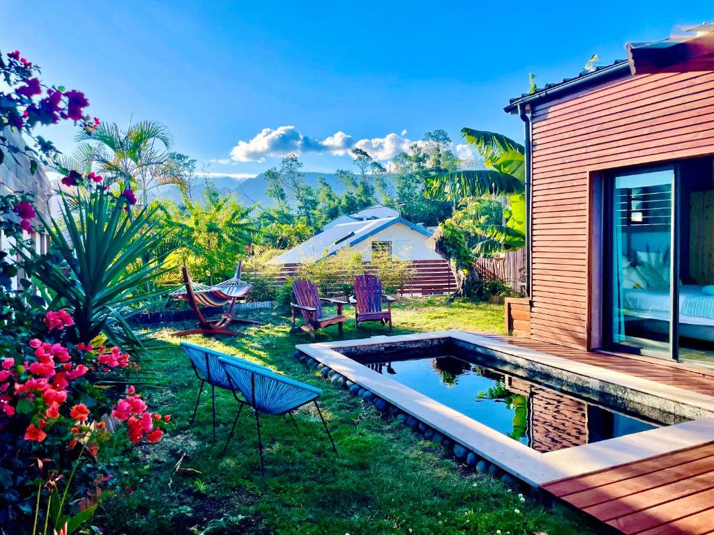 a backyard with a pool and chairs and a house at Anaélodge in Le Tampon