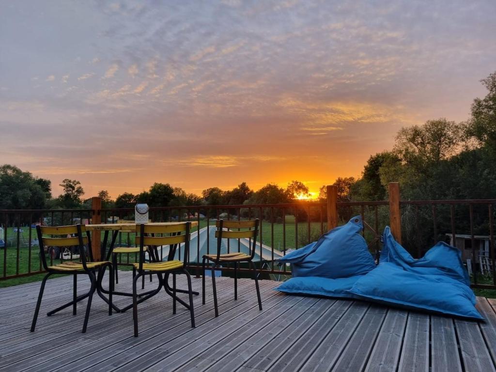 a table and chairs on a deck with a sunset at Zen suite Moulin de Vilaine in Châteauroux