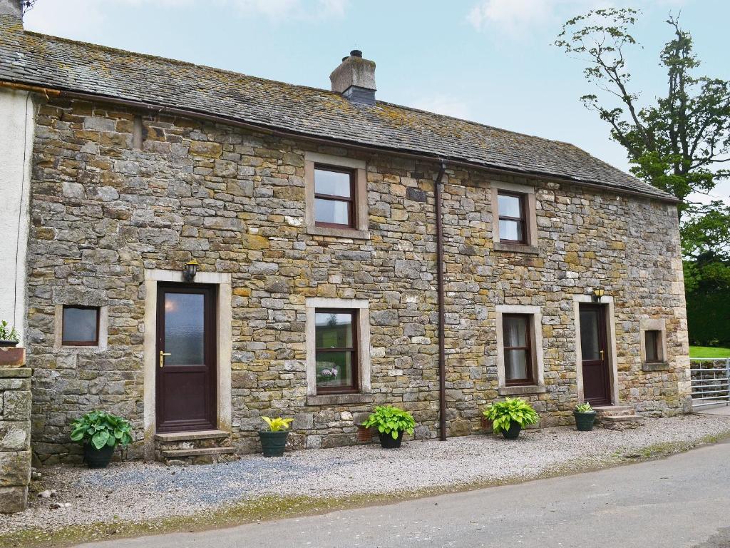 a stone house with potted plants in front of it at Swaledale Cottag in Caldbeck