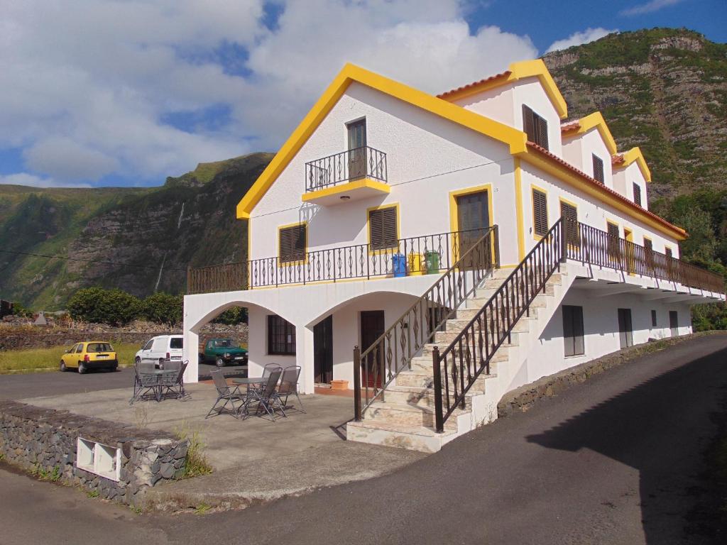 ein weißes Haus mit gelbem Dach und einem Parkplatz in der Unterkunft Casa da Sogra in Faja Grande