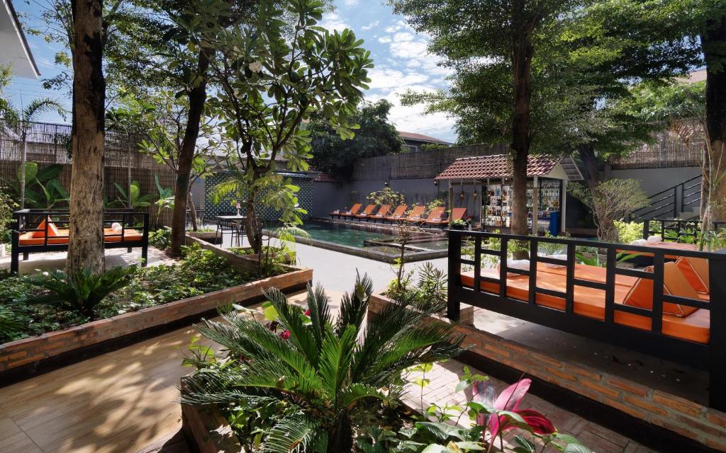 a garden with a pool and benches and trees at Indochine Sanctuary Boutique in Siem Reap