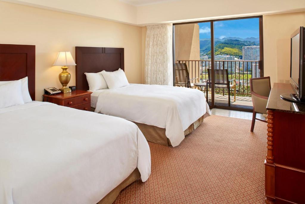 a hotel room with two beds and a balcony at Hilton Hawaiian Village Waikiki Beach Resort in Honolulu