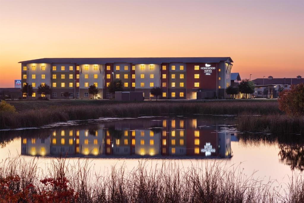 a building with lights on in front of a body of water at Homewood Suites TechRidge Parmer @ I-35 in Austin