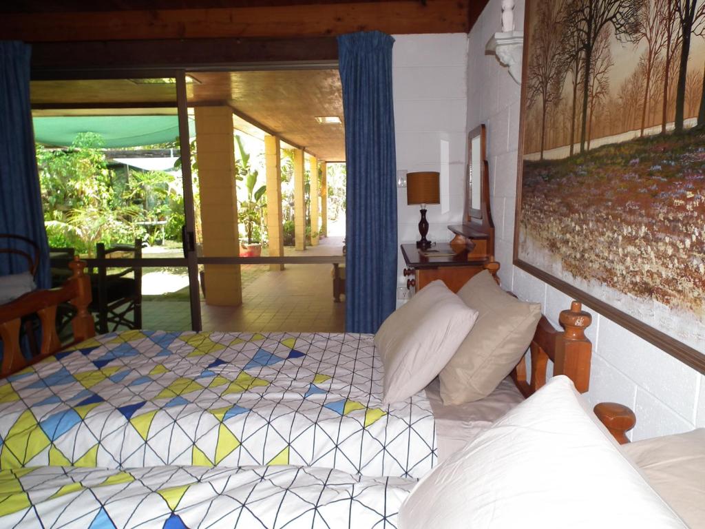 a bedroom with a bed, a chair, and a window at Shady Grove B&B in Hervey Bay