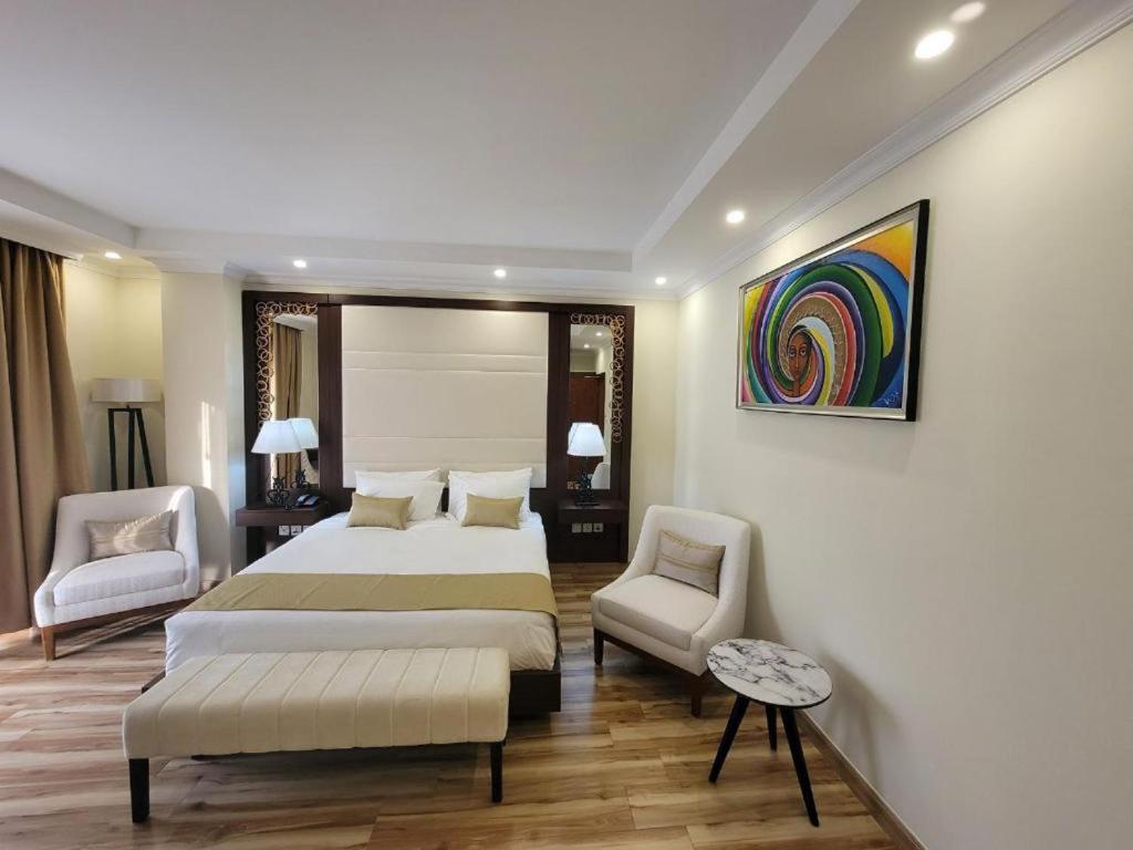 a bedroom with a large bed and two chairs at Goha Addis Hotel in Addis Ababa